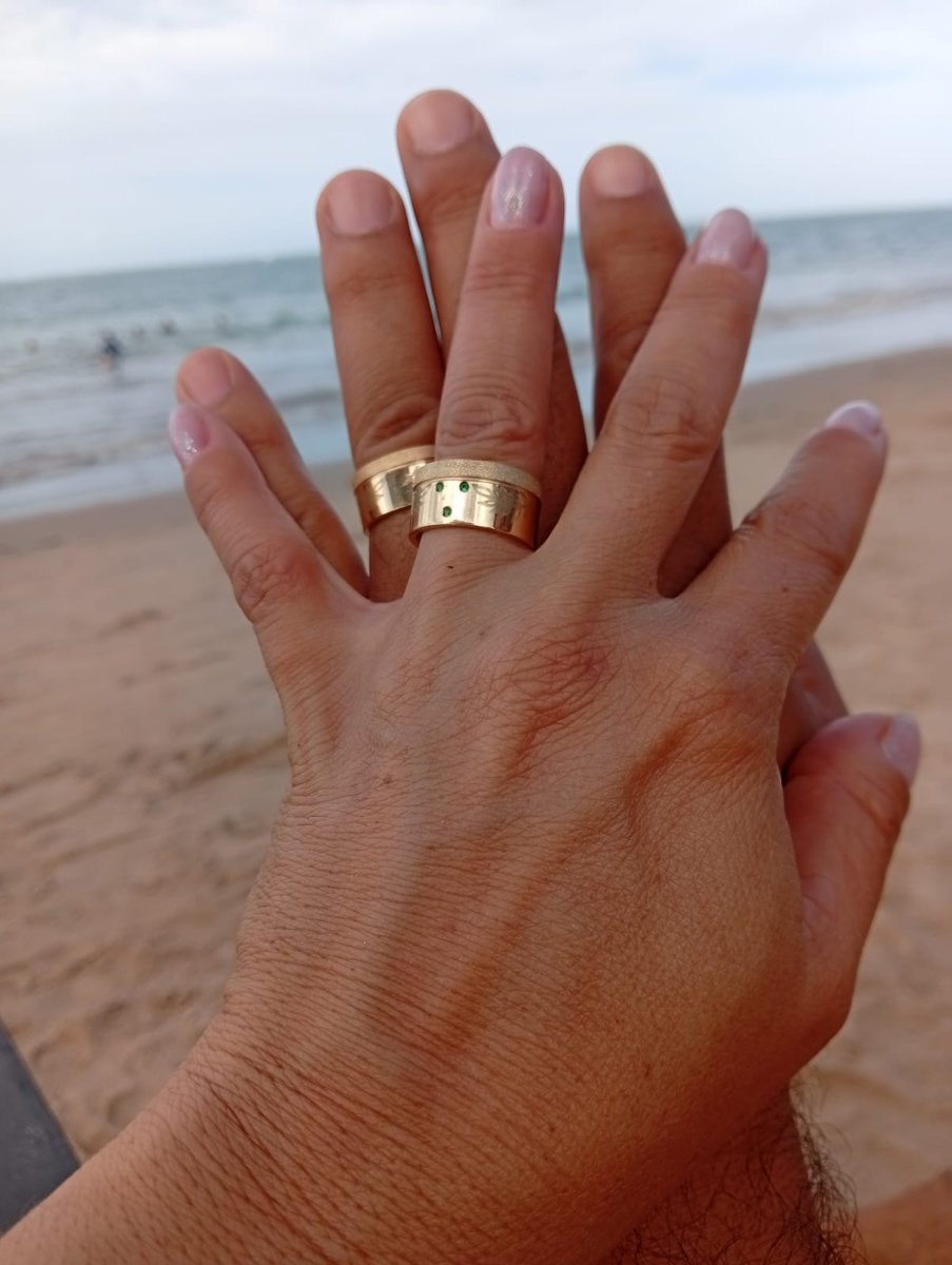 Casal usando alianças Joias Fittipaldi na praia